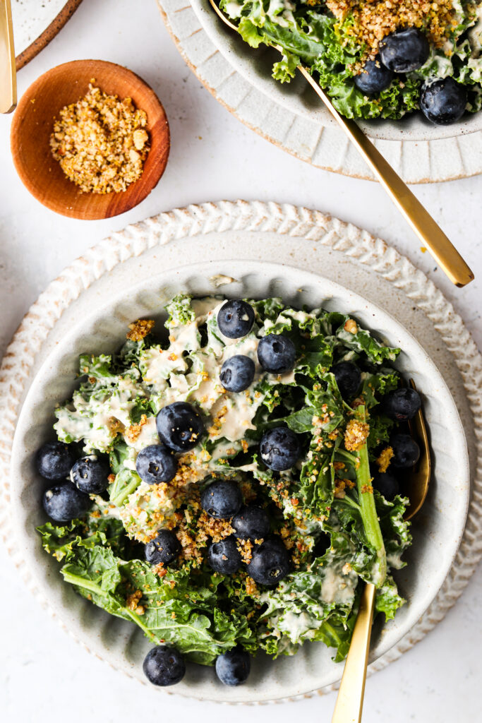 kale salad with pecan cheese and blueberries on top