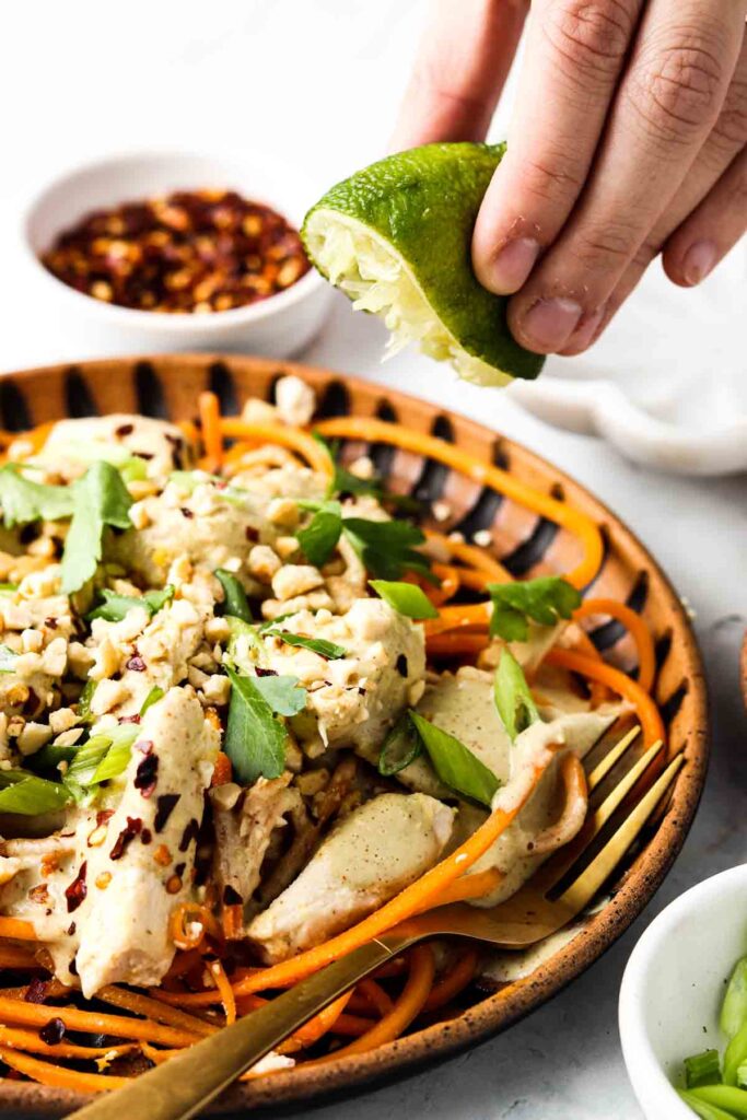 pad thai with a lime being squeezed on top