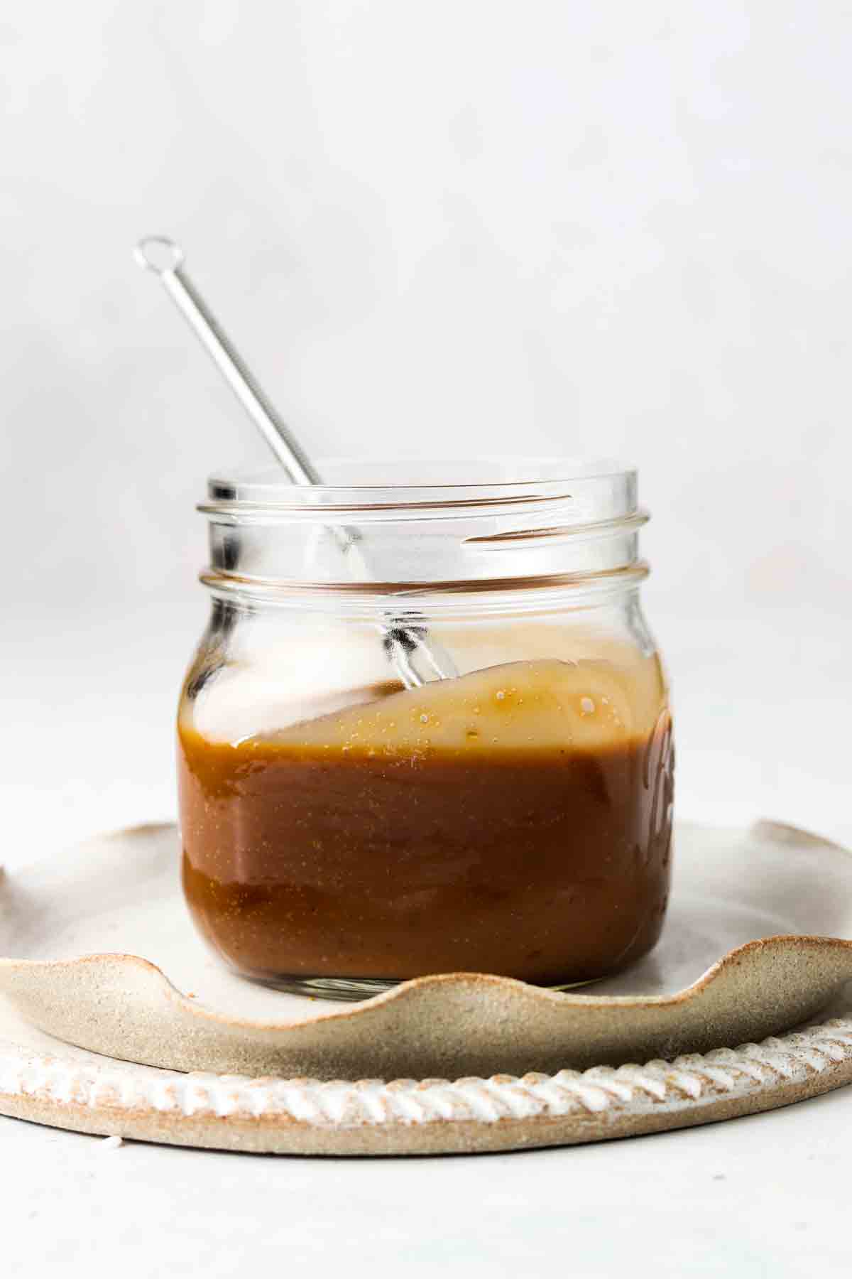 Caramel sauce on a jar with a small whisk.