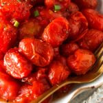 close up photo of tomatoes in the air fryer with seasoning on top