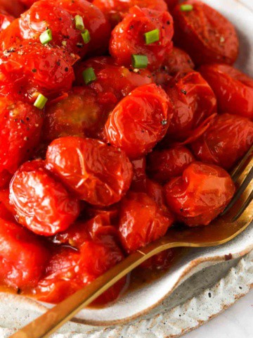 close up photo of tomatoes in the air fryer with seasoning on top