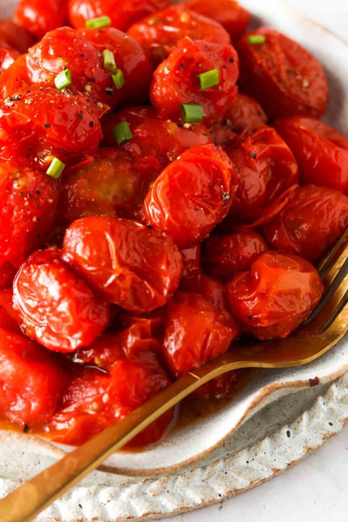 close up photo of tomatoes in the air fryer with seasoning on top