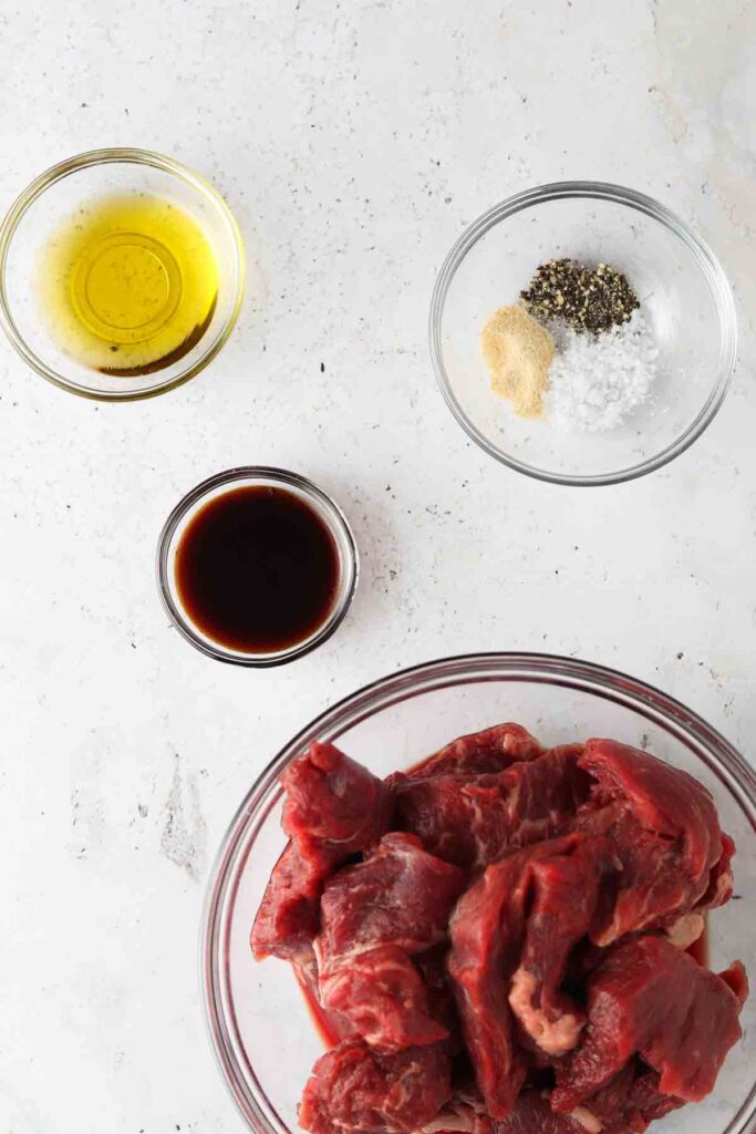 raw steak, oil and spices laid out in bowls