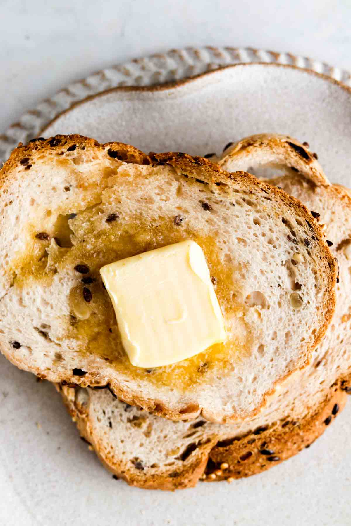 Toast on a plate with a pad of butter.