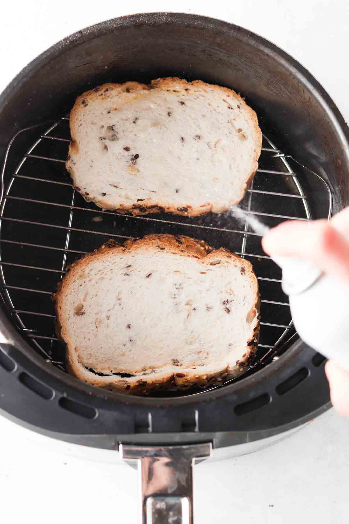 Spraying cooking oil spray on bread.