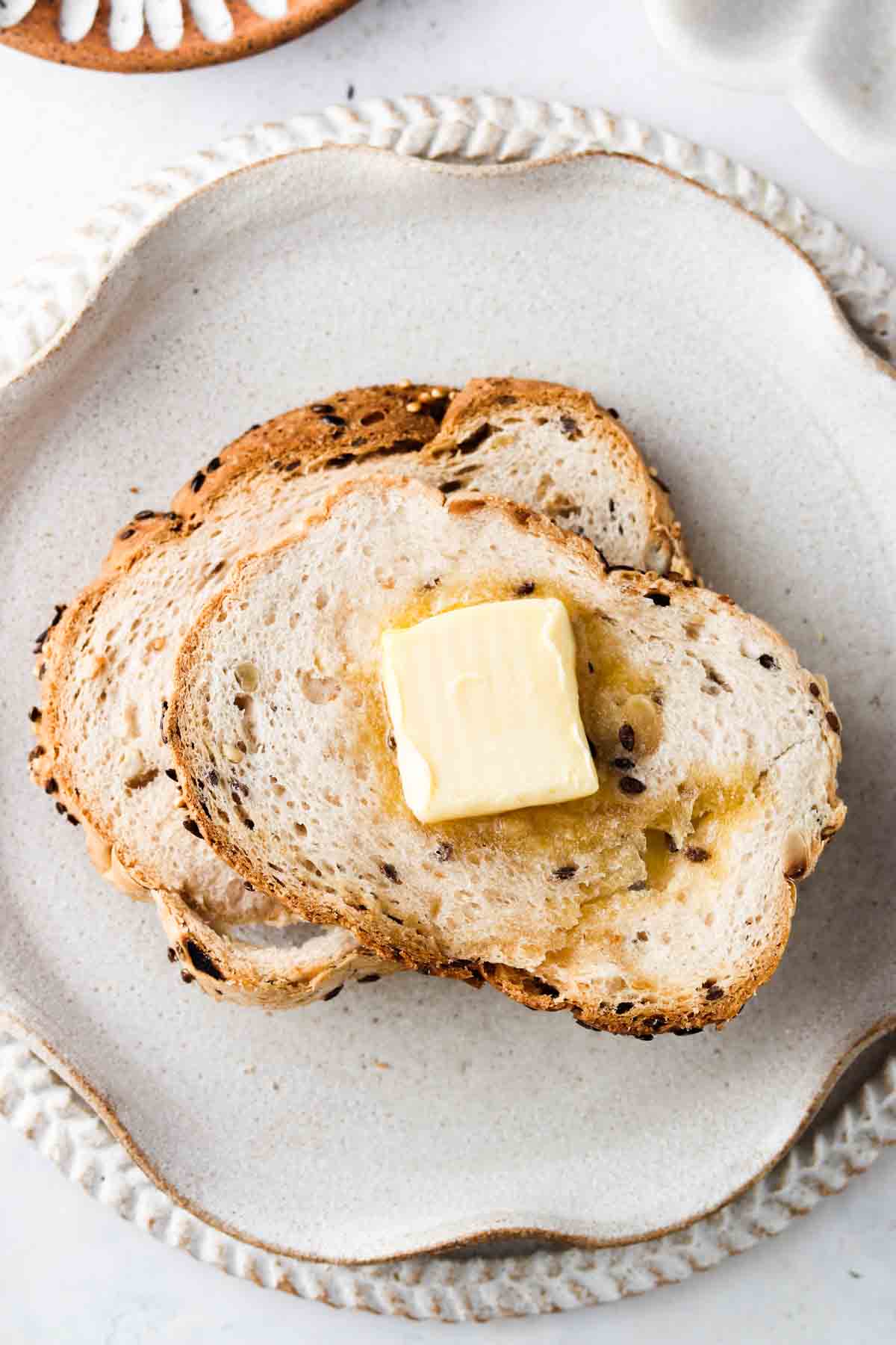 Air fryer toast on a plate with a pad of ghee on top.