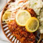 blackened pork on a plate with lemons and mashed potatoes