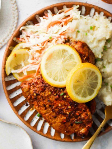 blackened pork on a plate with lemons and mashed potatoes