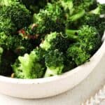 Broccoli in a bowl with red pepper flakes and salt on top.