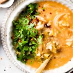 cauliflower and leek soup in a bowl with fresh herbs on top