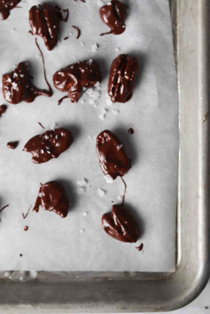 chocolate covered pecans on a baking sheet