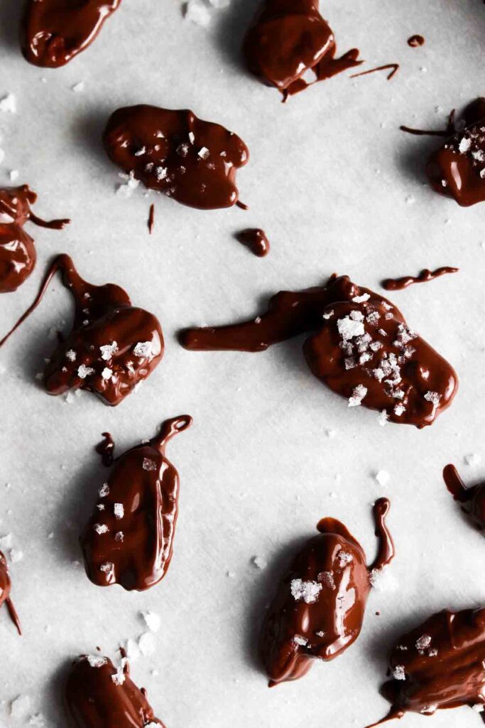 chocolate covered pecans on a baking sheet with sea salt