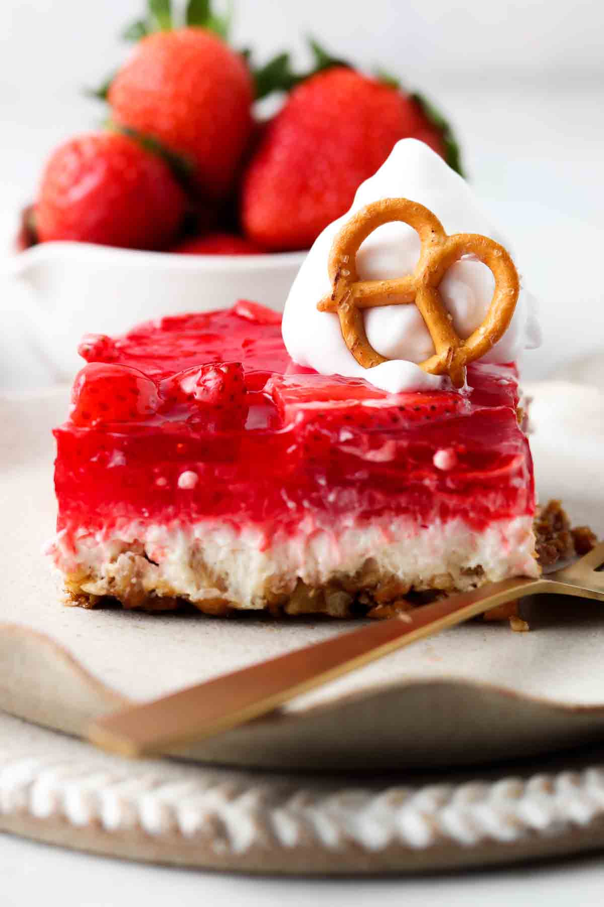Dairy free strawberry pretzel salad on a plate with whipped cream on top.