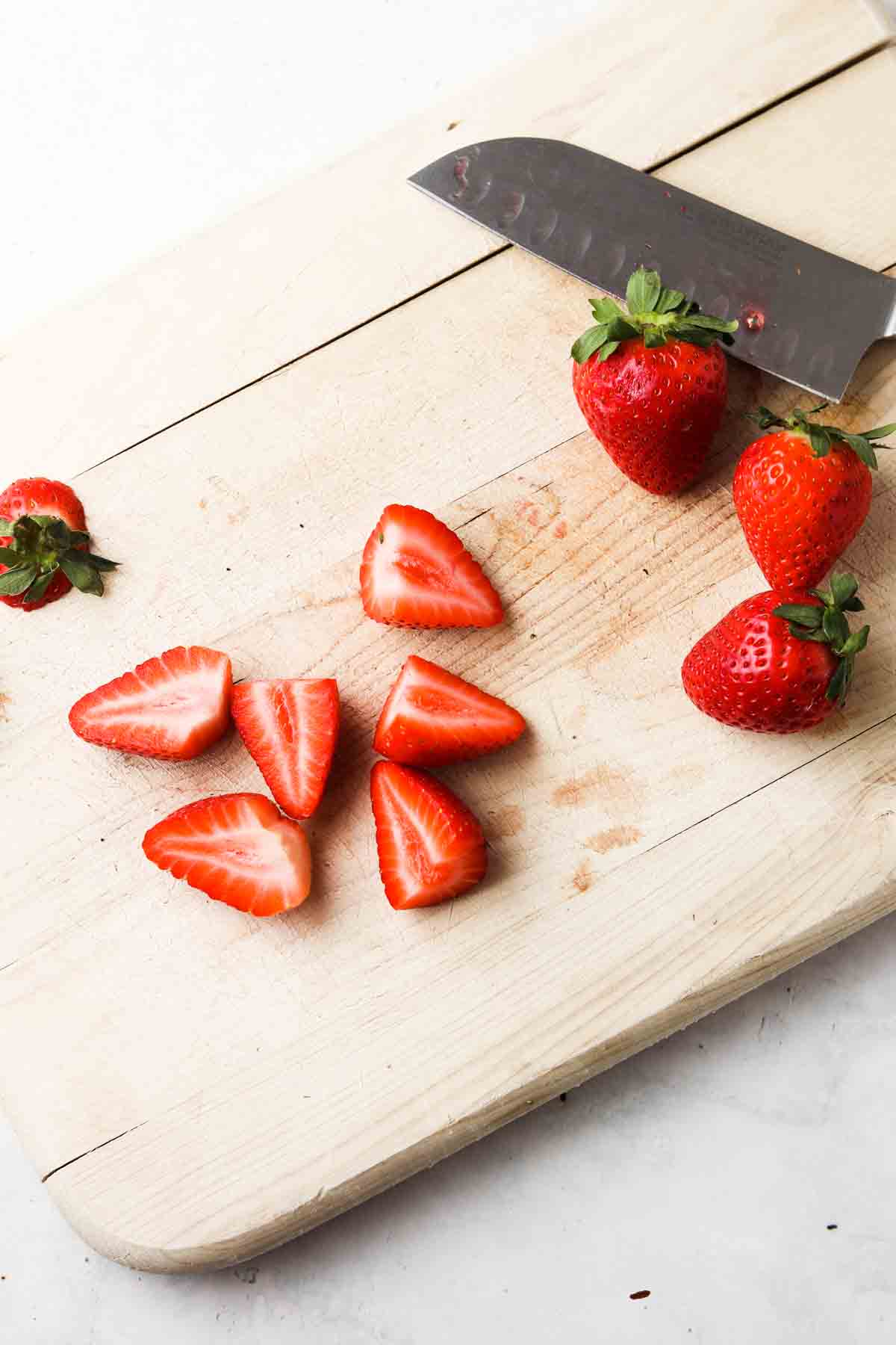 Sliced up strawberries on a cutting board.