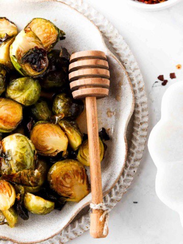 brussel sprouts on a plate with a honey wand