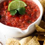 keto salsa in a bowl with a lime and cilantro on top with low carb chips on the side