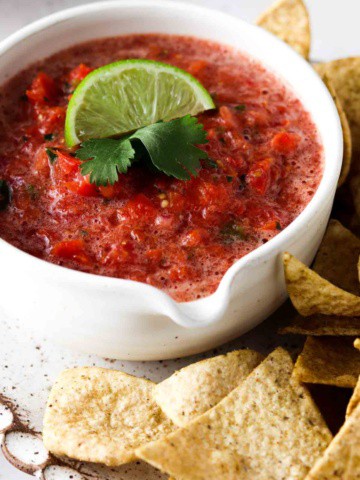 keto salsa in a bowl with a lime and cilantro on top with low carb chips on the side