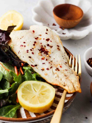 air fried cod on a plate with mixed greens