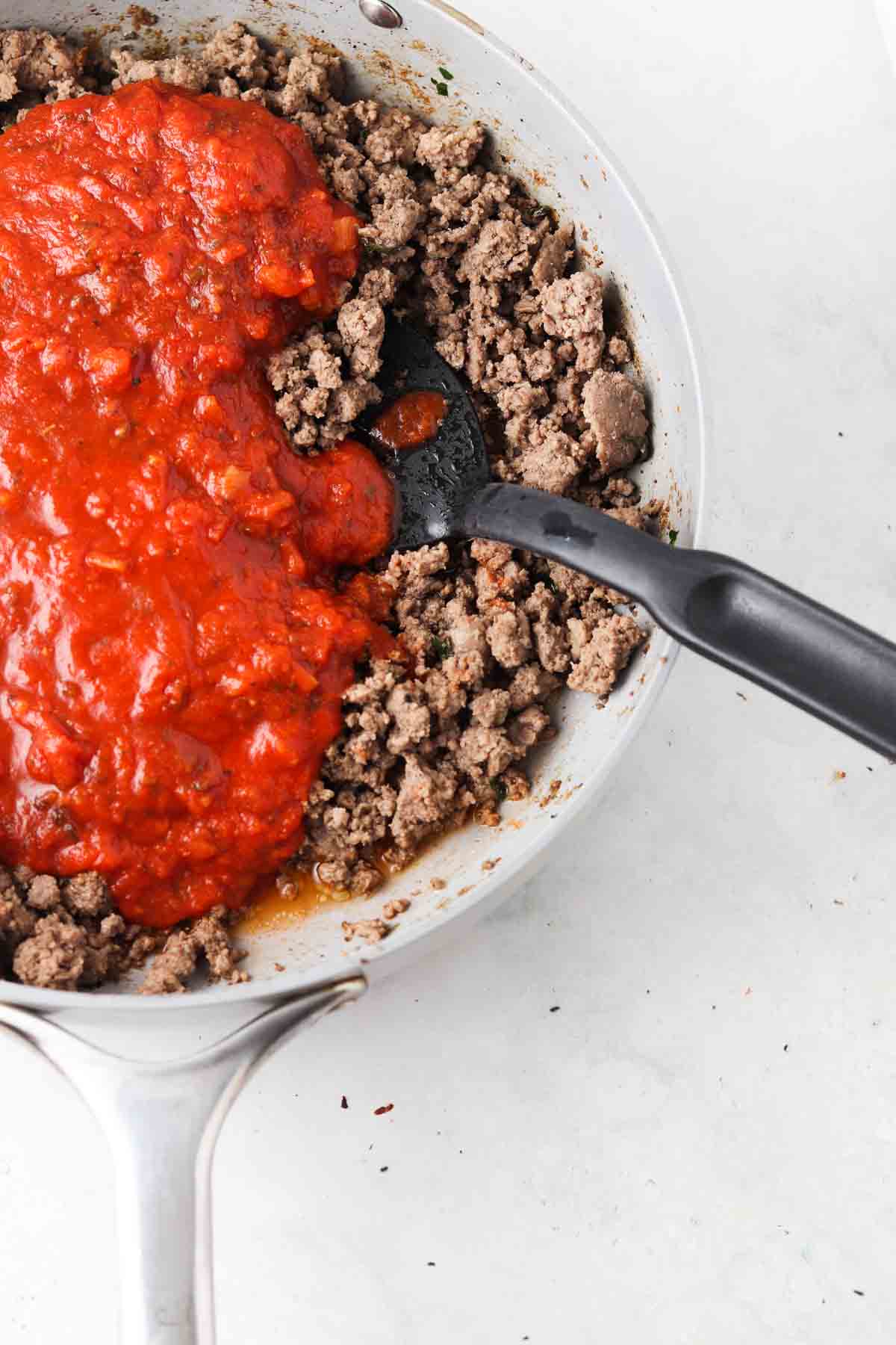 Ground beef in a skillet with red sauce and spices.