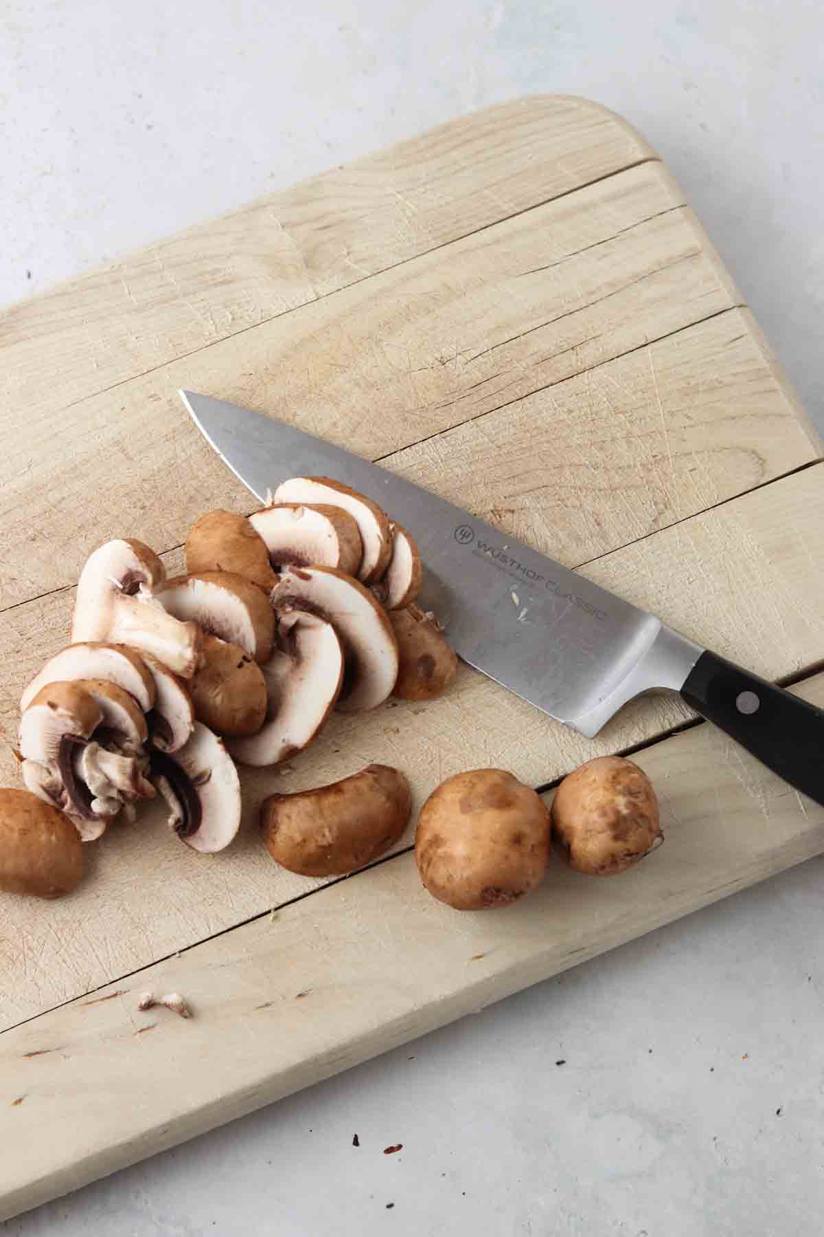 Mushrooms on a cutting board with a knife. 