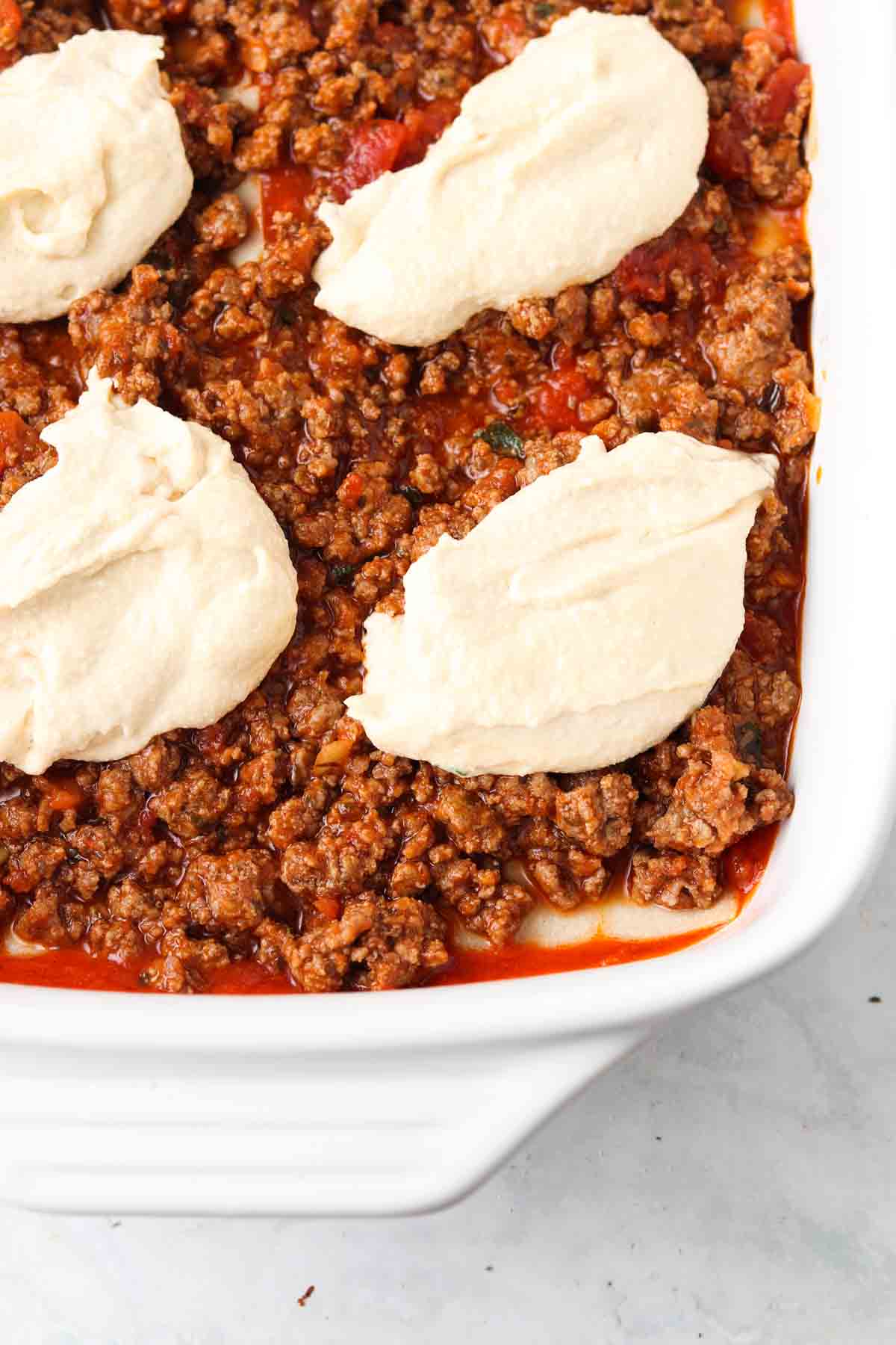 A layer of cheese on top of lasagna meat sauce. 