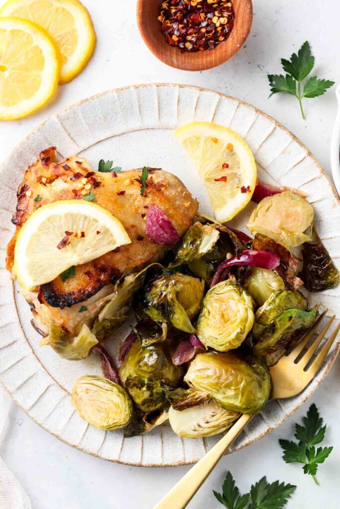 chicken thighs and brussel sprouts on a plate with honey mustard and lemons