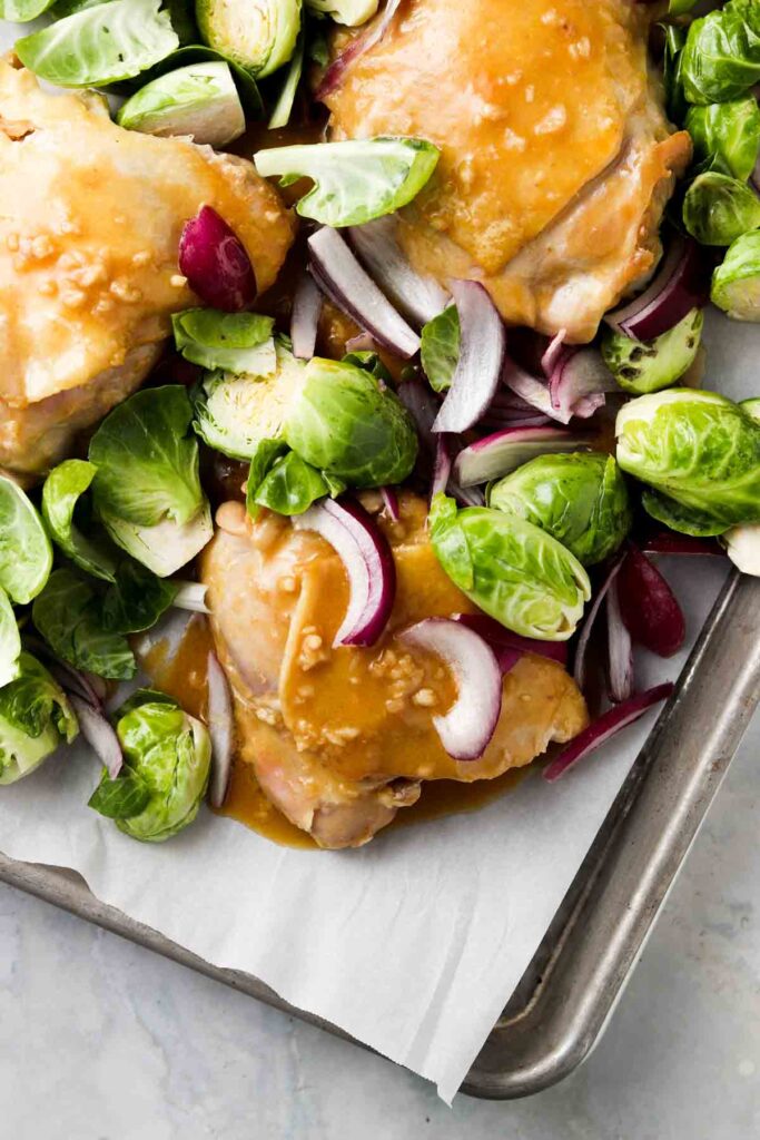 raw chicken and brussel sprouts in a sheet pan