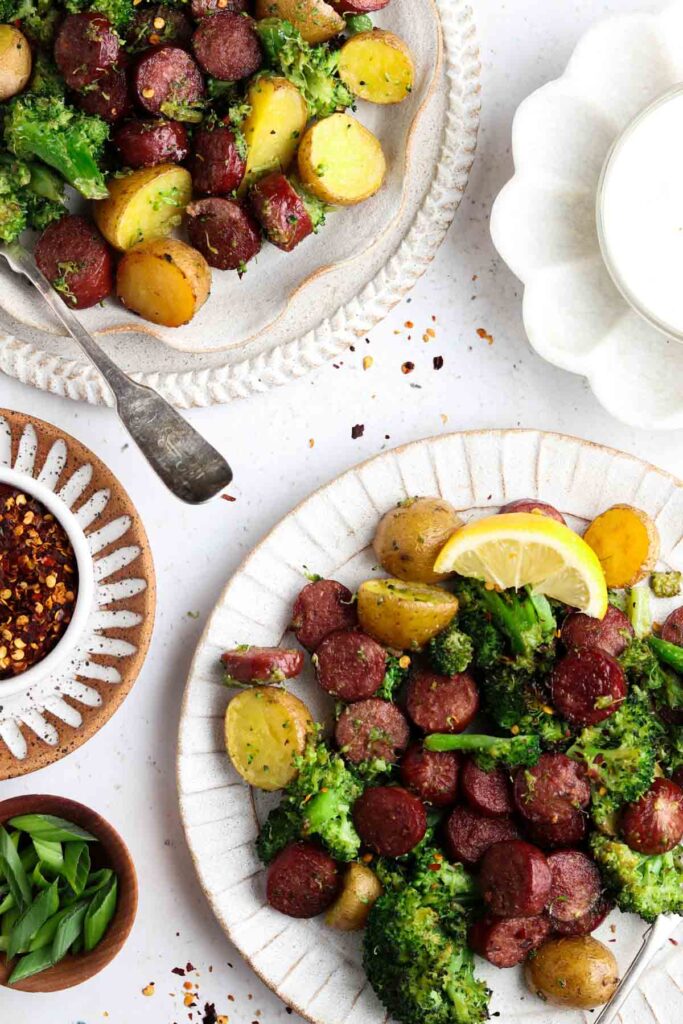 overhead shot of sausage, potatoes, broccoli and garlic aioli on two plates