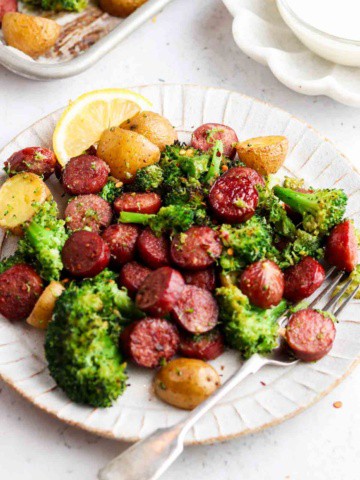 sausage, broccoli and potatoes on a plate with a fork and garlic aioli