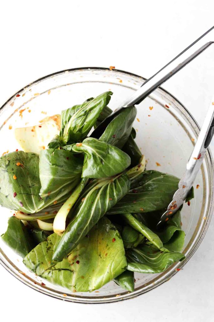 tongs in a bowl with bok choy