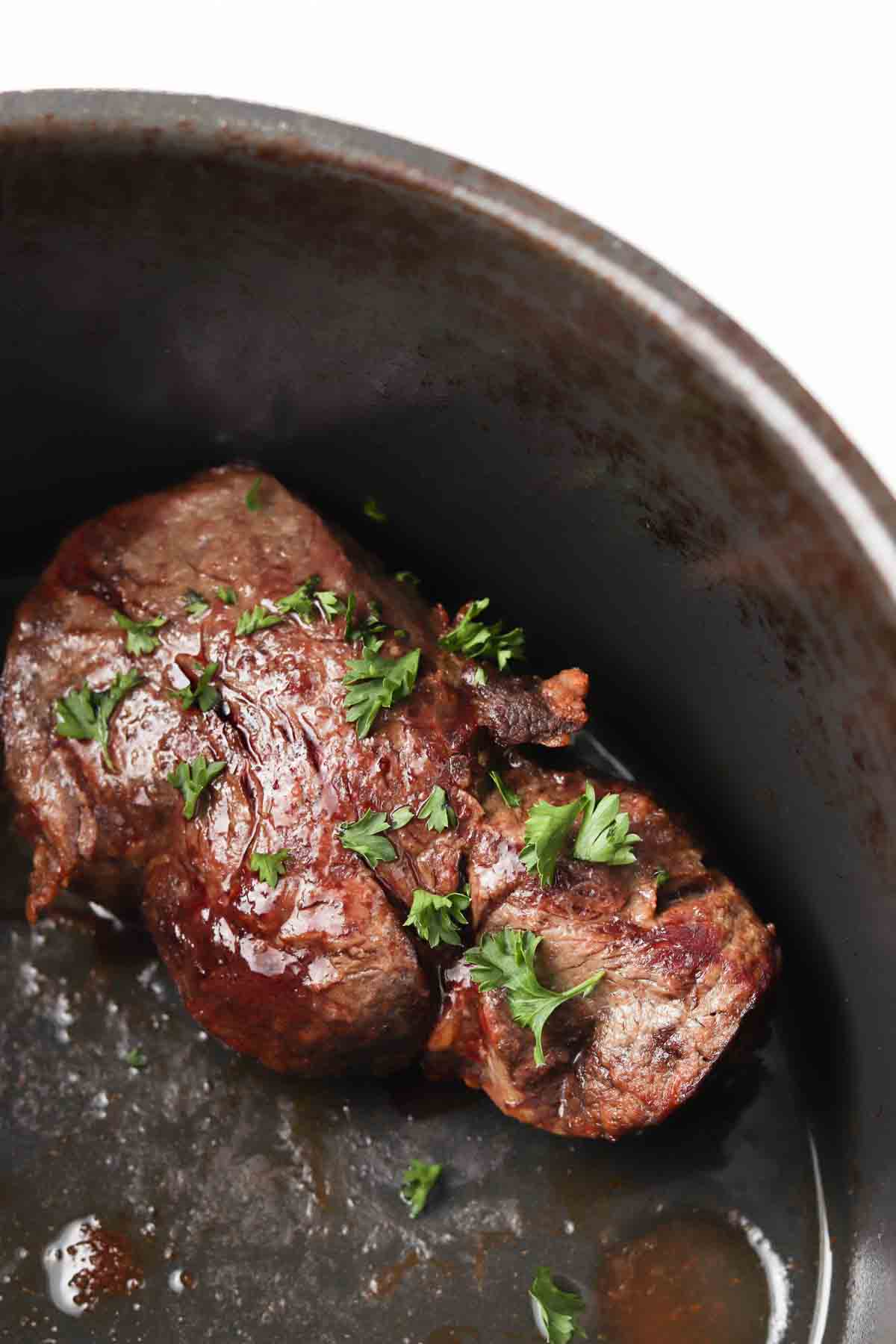 Steak in the air fryer with a garnish on top.