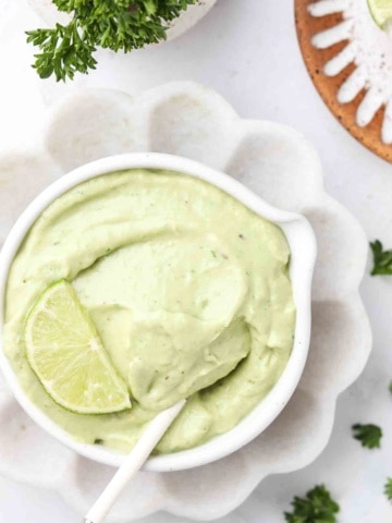 avocado lime ranch dressing in a bowl with a lime on top