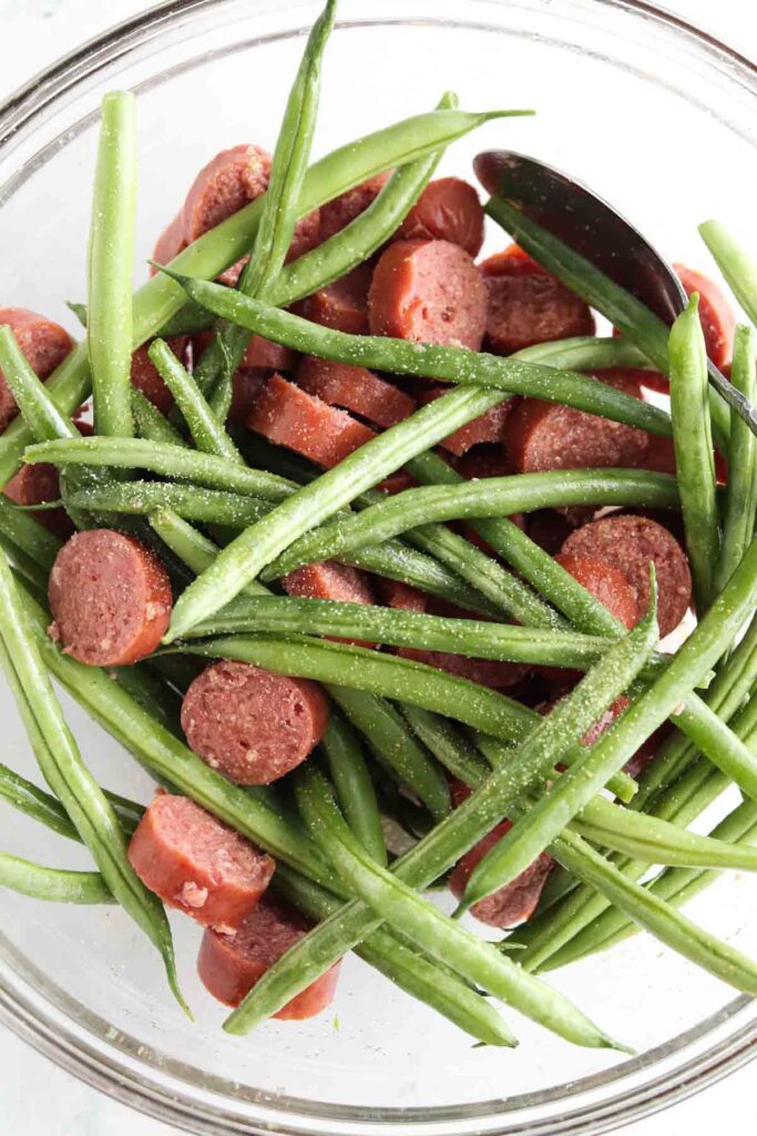 chopped up sausage and green beans in a bowl