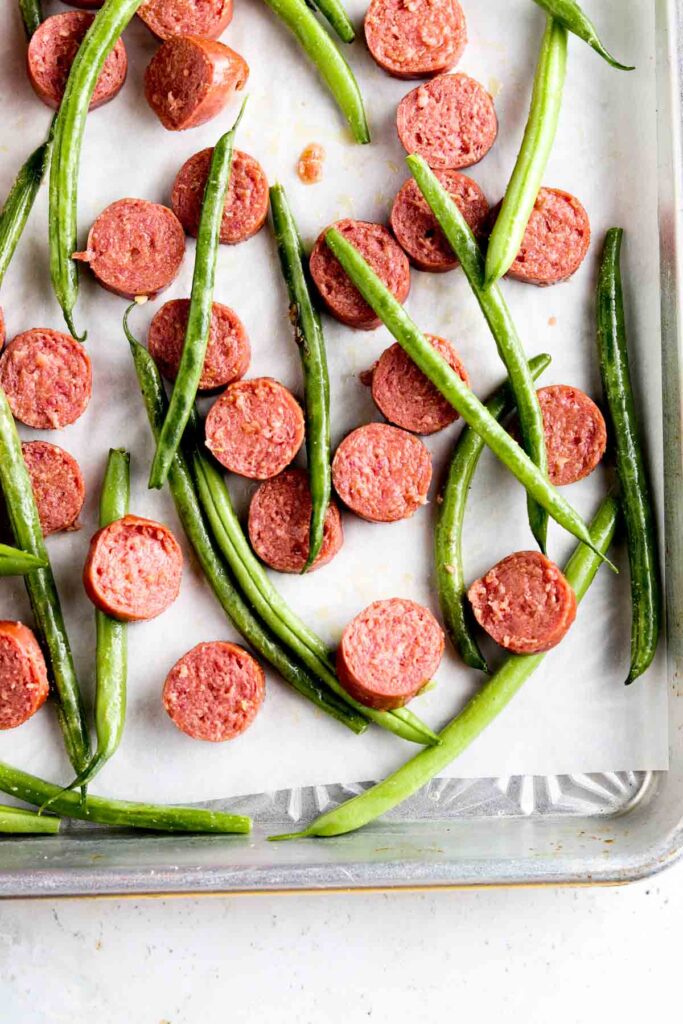 chopped sausage and green beans on a sheet pan