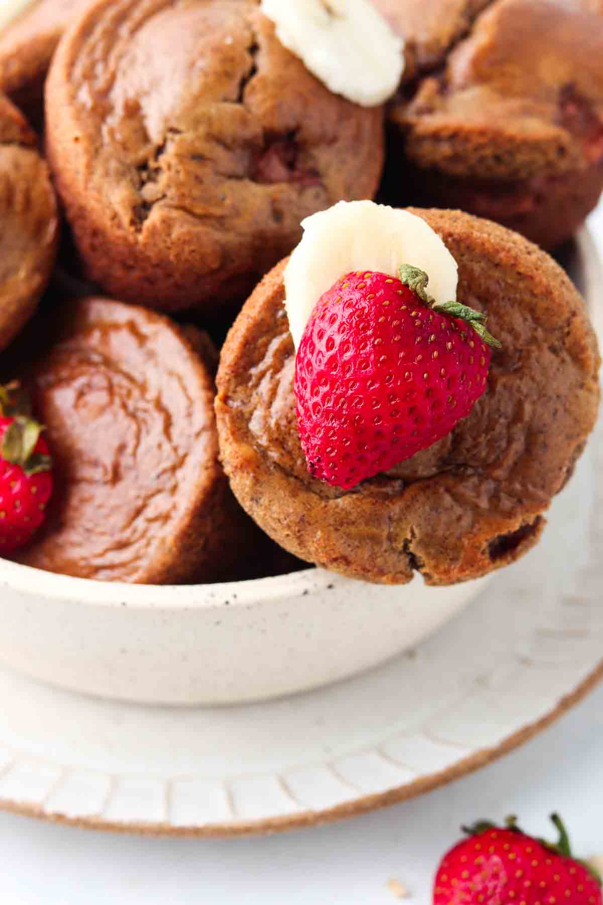 Strawberry muffins garnished with banana slices and fresh strawberries.