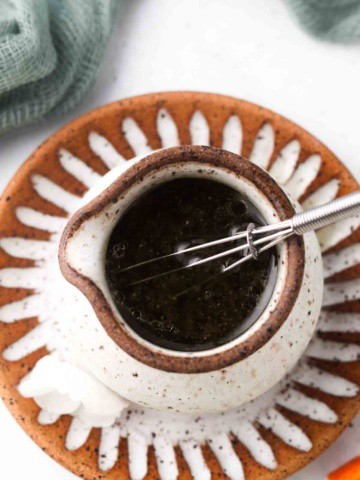 orange poppyseed salad dressing in a bowl with a whisk