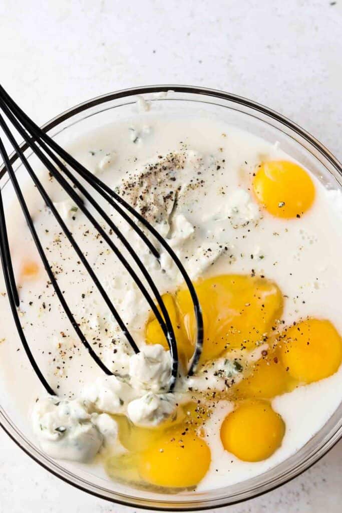 cream cheese, eggs and milk in a bowl