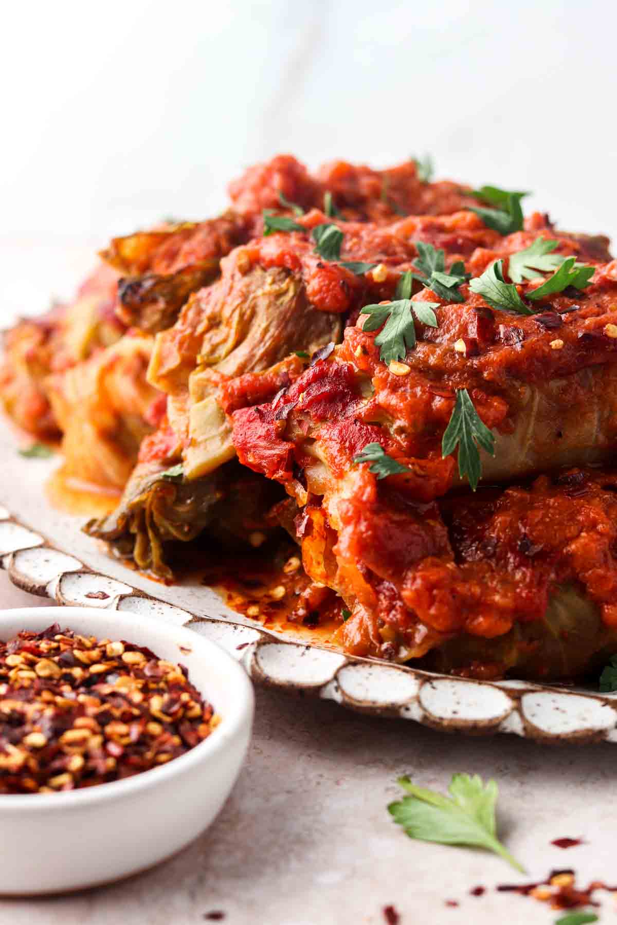 Side view of stuffed cabbage on a plate with fresh parsley on top.