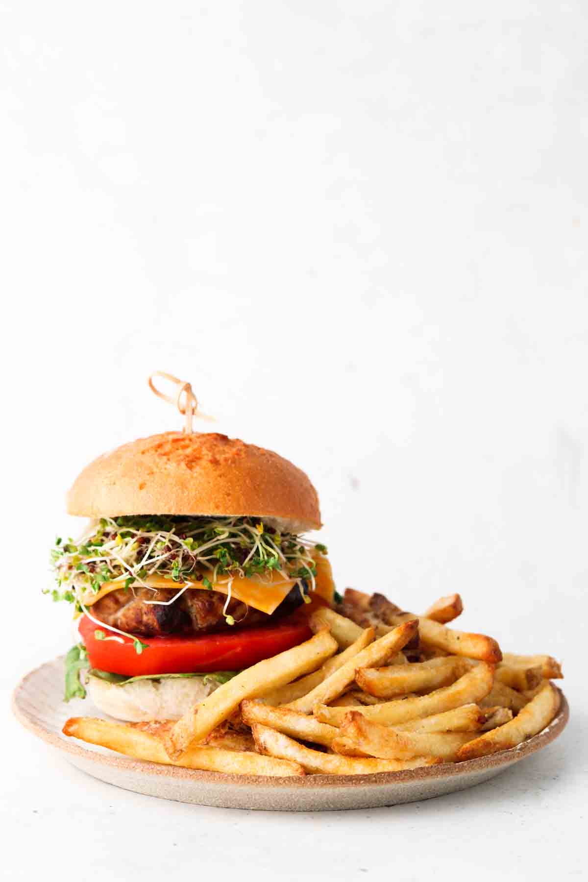 An air fried turkey burger on a plate with french fries. 