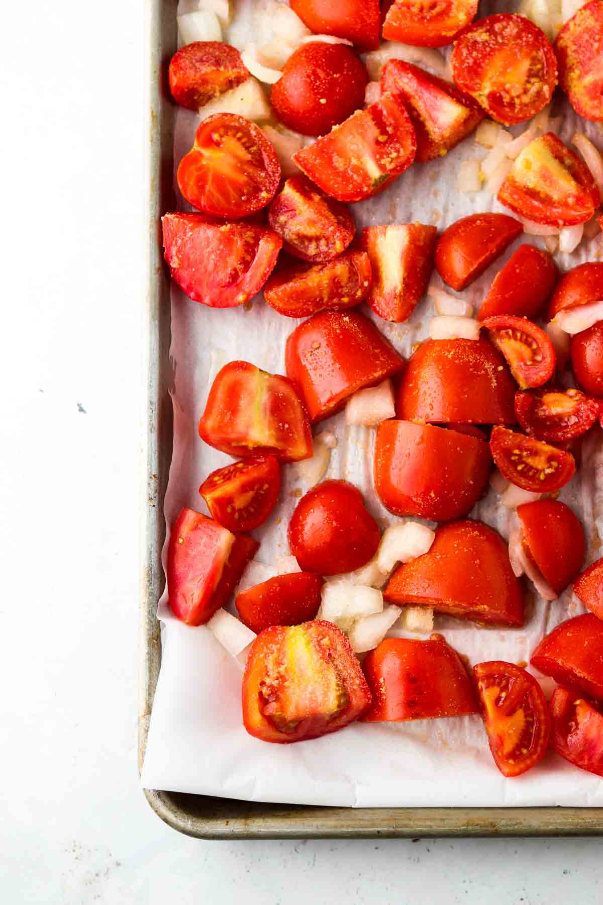 Diced up tomatoes and onions on a sheet pan.