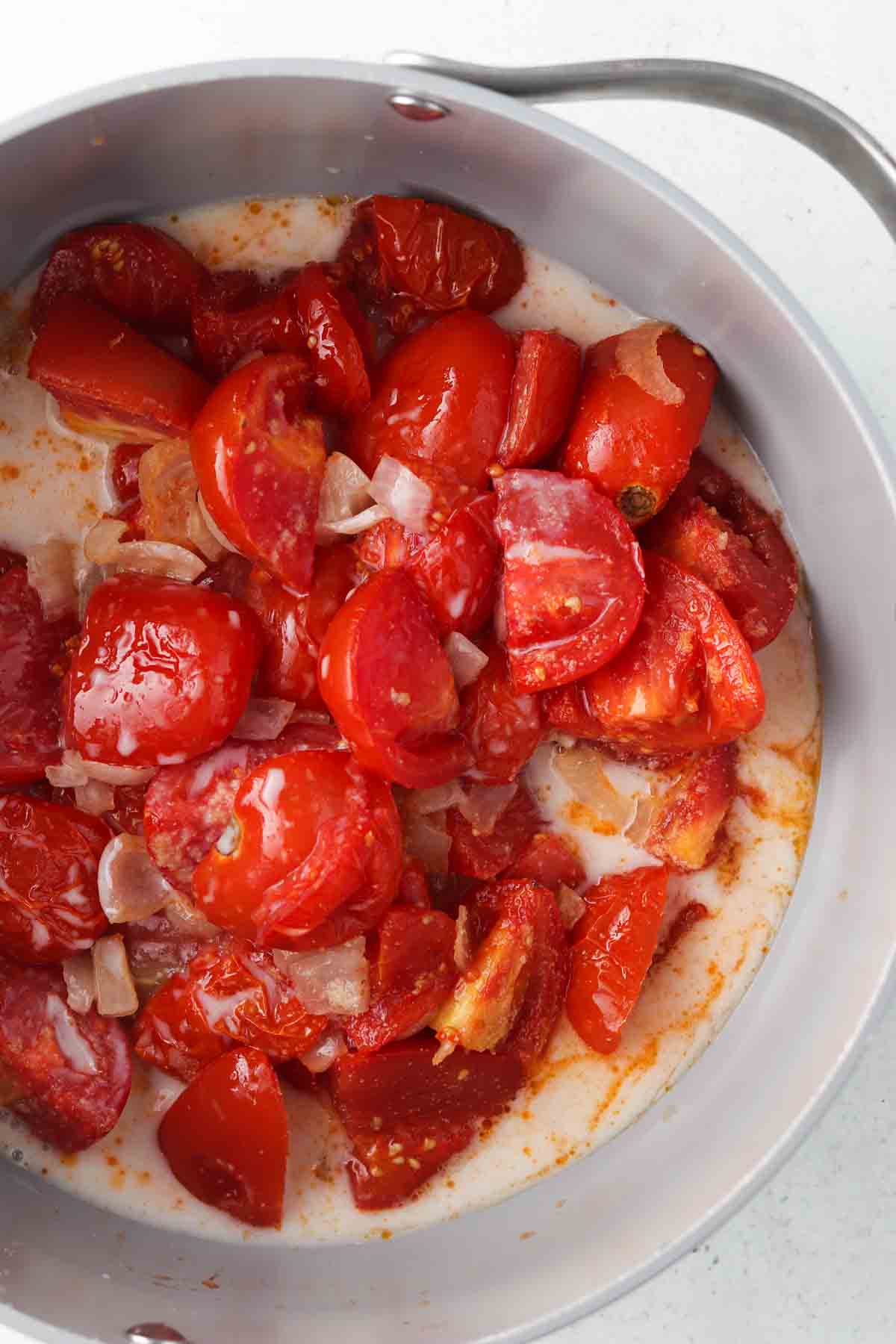 Coconut milk and tomatoes in a soup pot.