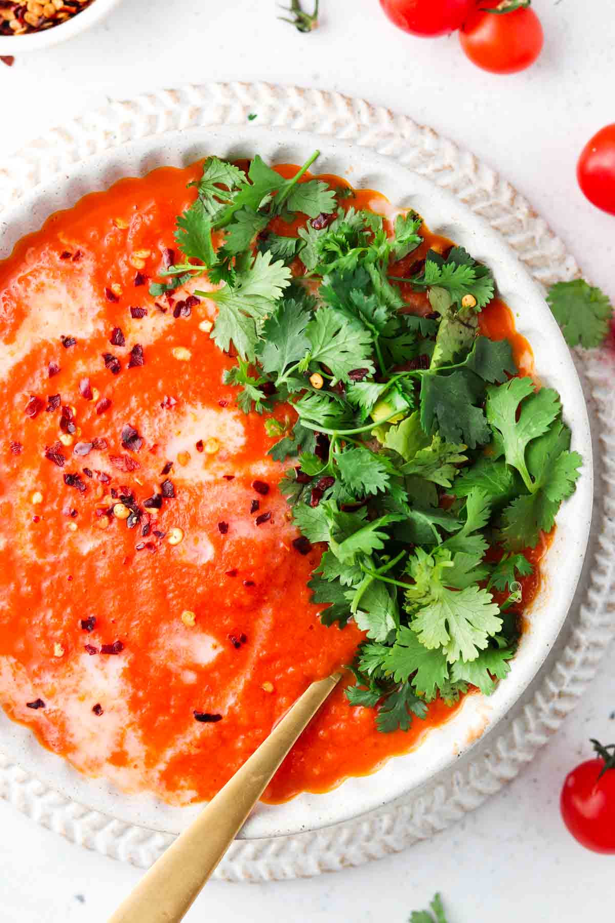 Tomato soup in a pretty braided bowl with fresh parsley on top.