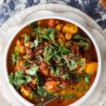 Chickpea curry in a bowl with fresh herbs on top.