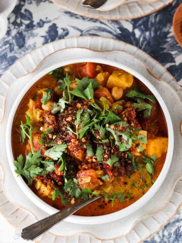 Chickpea curry in a bowl with fresh herbs on top.