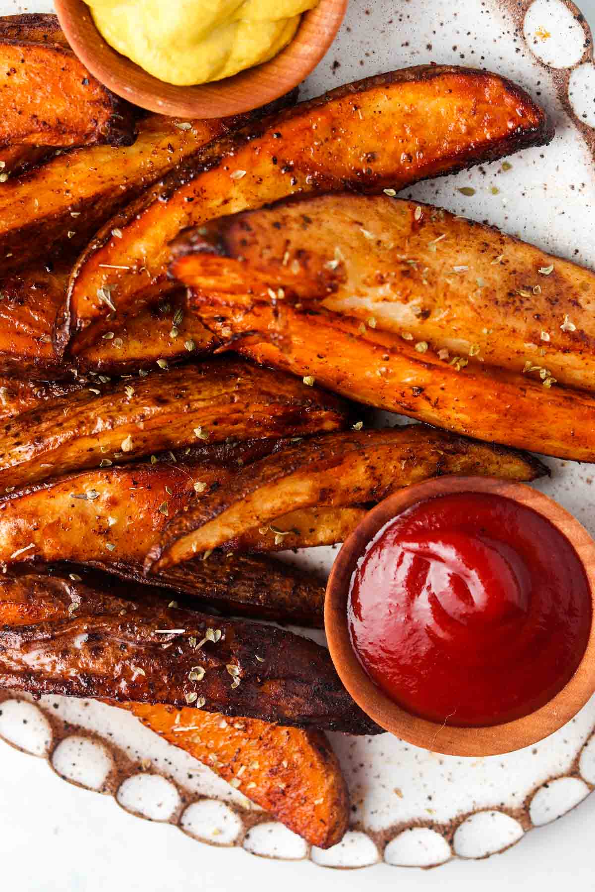 Air fried potato wedges on a plate with sauces.