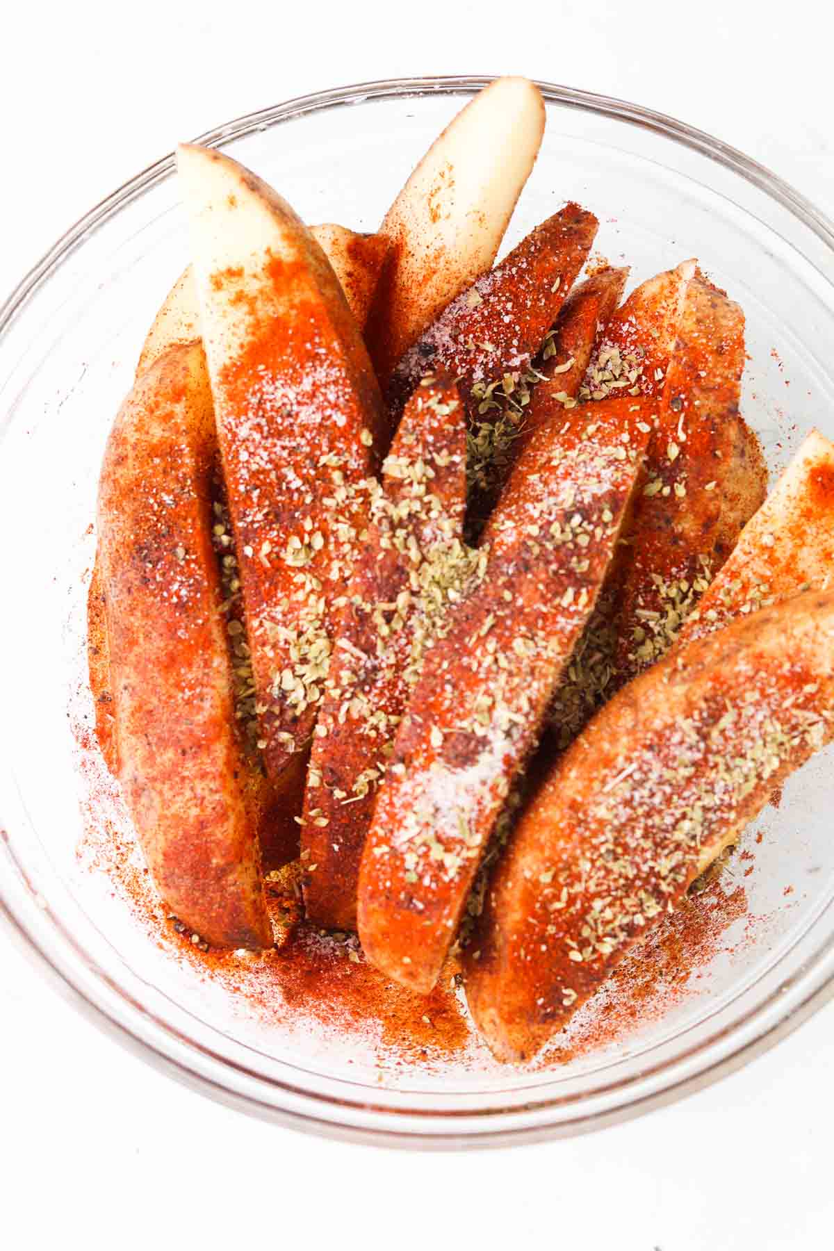 Potato wedges with seasoning on top.