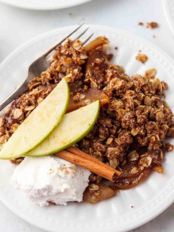 apple crisp on a plate with whipped cream