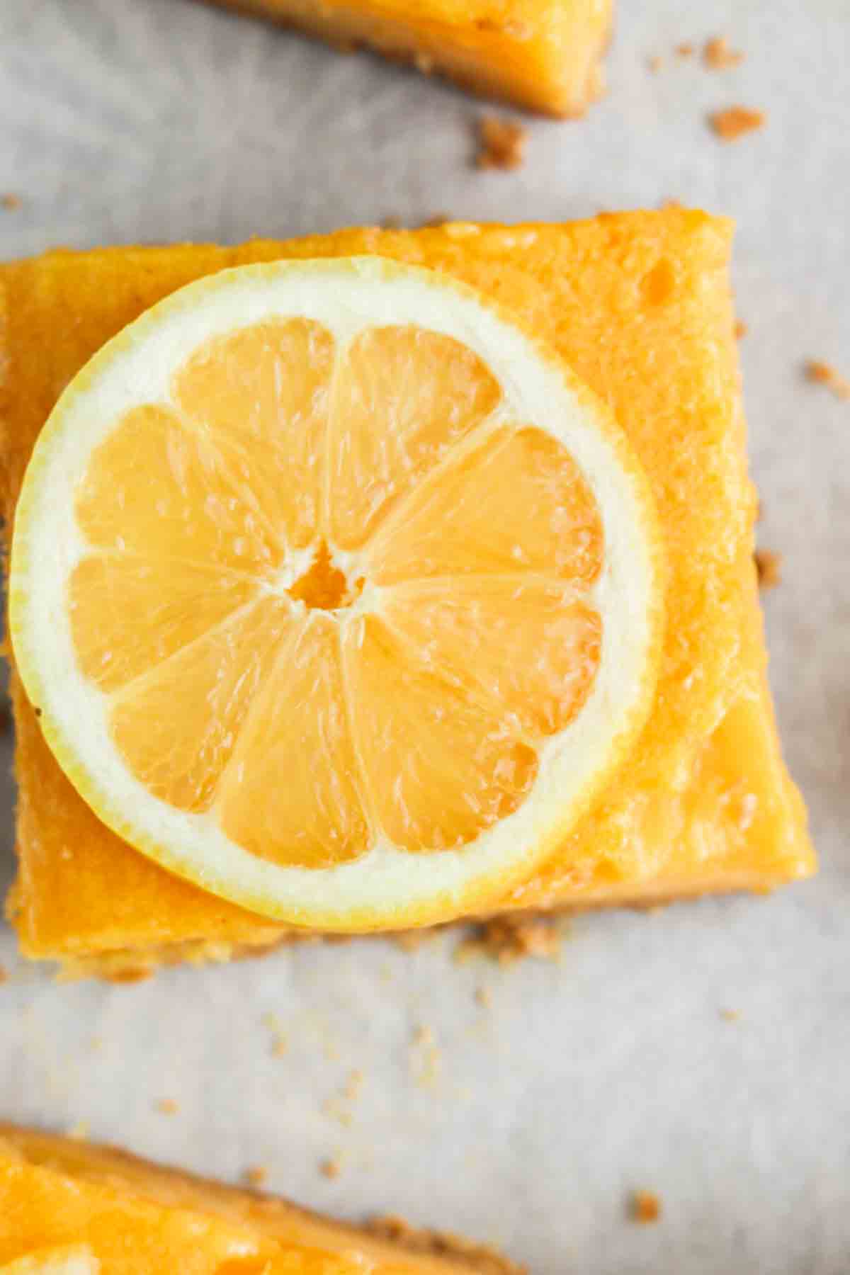 Close up photo of a lemon bar with a sliced lemon on top.