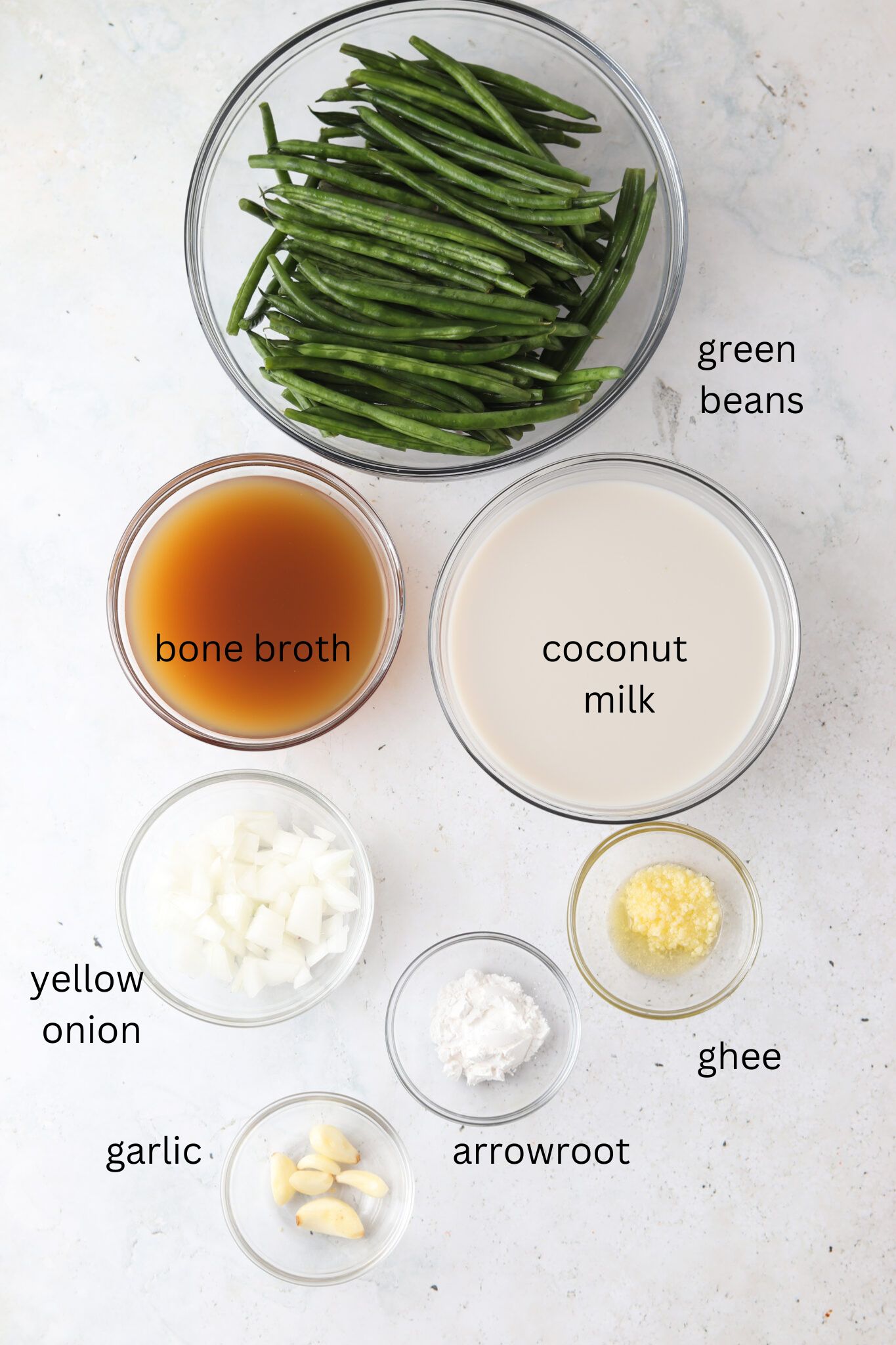 Dairy free green bean casserole ingredients laid out in glass bowls on a counter. 