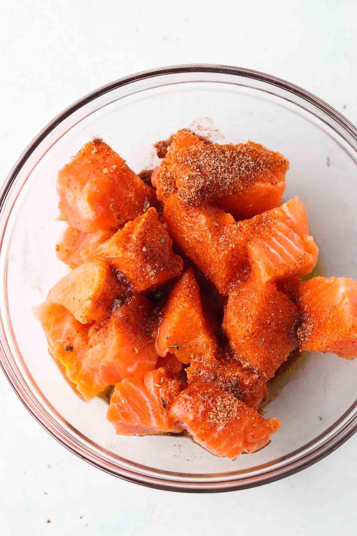 Salmon bites with dry ingredients in a glass bowl.